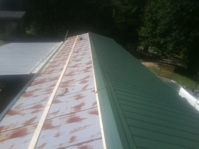 Old rusted panels beside newly installed green metal roofing — Wind Damage Roof Repair by Roofing Brothers in Newman Lake