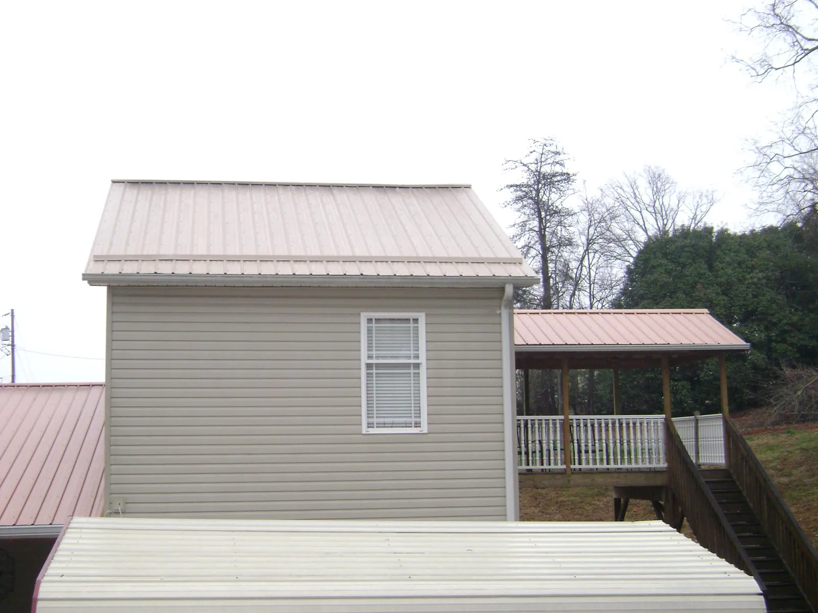 Tan metal roofs on a two story addition and attached porch, from a Roof Replacement job in Newman Lake