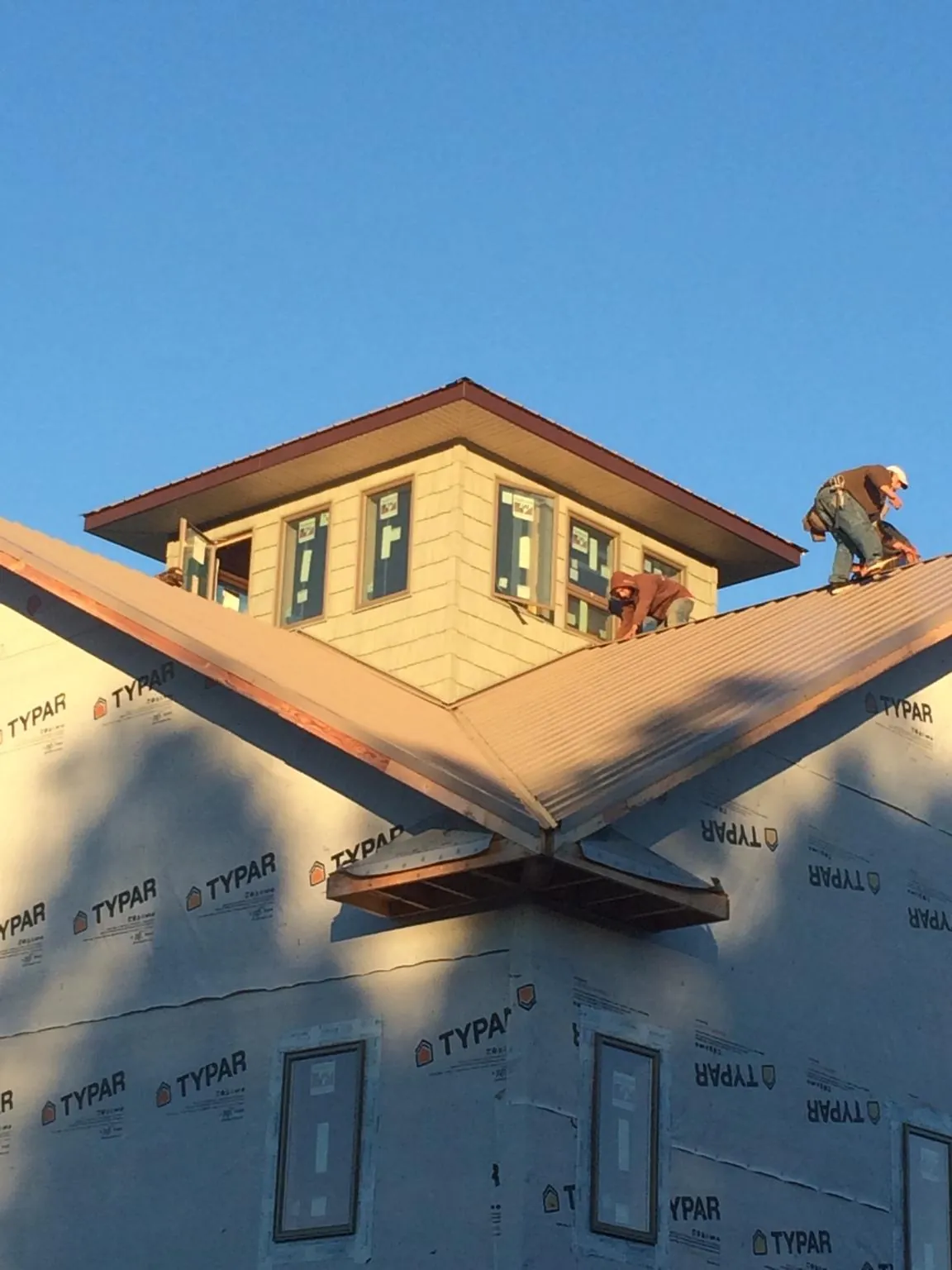 Roofers working around a rooftop cupola on a new metal roof at sunset — Roof Waterproofing in Newman Lake by Roofing Brothers